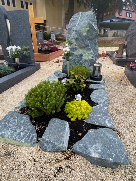 Einzelgrab mit grob behauenem Stein als Grabeinfassung und Grabstein